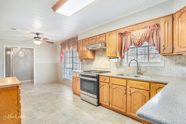 kitchen featuring backsplash, stainless steel gas stove, plenty of natural light, and sink