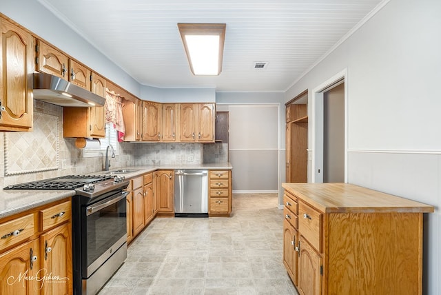 kitchen with butcher block countertops, sink, stainless steel appliances, and tasteful backsplash