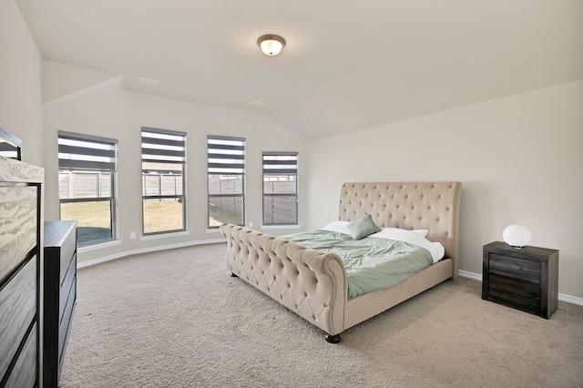 bedroom with vaulted ceiling, light carpet, and multiple windows