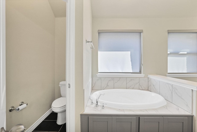 bathroom featuring tile patterned flooring, a tub to relax in, and toilet