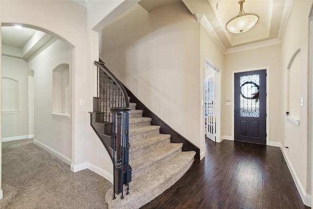 entrance foyer with dark hardwood / wood-style flooring, ornamental molding, and a high ceiling