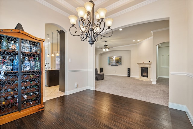 unfurnished dining area featuring ceiling fan with notable chandelier, sink, crown molding, and light carpet