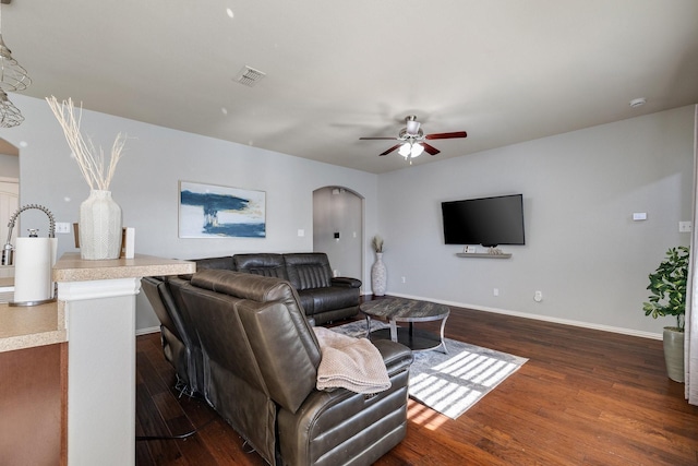 living room with ceiling fan and dark wood-type flooring