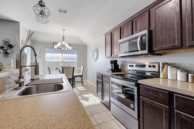 kitchen featuring lofted ceiling, sink, light tile patterned floors, appliances with stainless steel finishes, and a chandelier