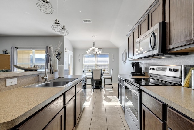 kitchen featuring lofted ceiling, sink, light tile patterned floors, appliances with stainless steel finishes, and a chandelier