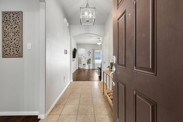 tiled entryway featuring ceiling fan with notable chandelier