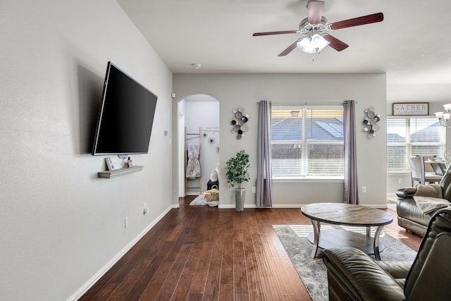 living room with ceiling fan with notable chandelier and dark hardwood / wood-style flooring