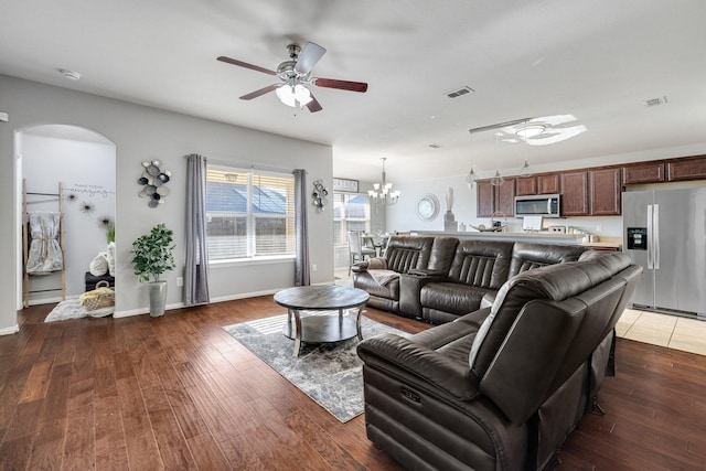 living room with ceiling fan with notable chandelier and dark wood-type flooring