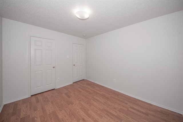 unfurnished bedroom with a textured ceiling, hardwood / wood-style flooring, and a closet