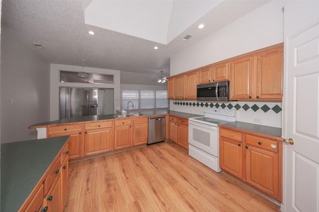 kitchen with lofted ceiling, sink, decorative backsplash, kitchen peninsula, and stainless steel appliances