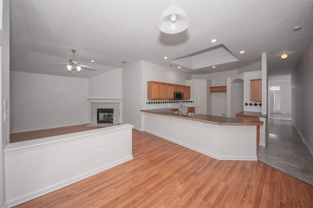 kitchen featuring a tile fireplace, sink, kitchen peninsula, light hardwood / wood-style floors, and a textured ceiling