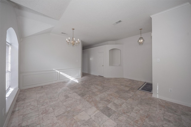 empty room featuring lofted ceiling, a textured ceiling, an inviting chandelier, and crown molding