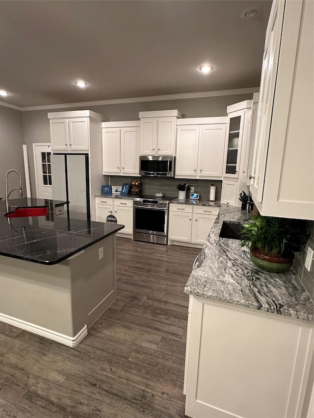 kitchen featuring white cabinetry, stainless steel appliances, sink, and dark stone counters