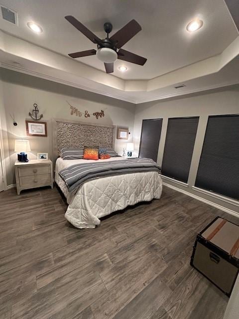 bedroom featuring ceiling fan, a tray ceiling, and dark hardwood / wood-style flooring