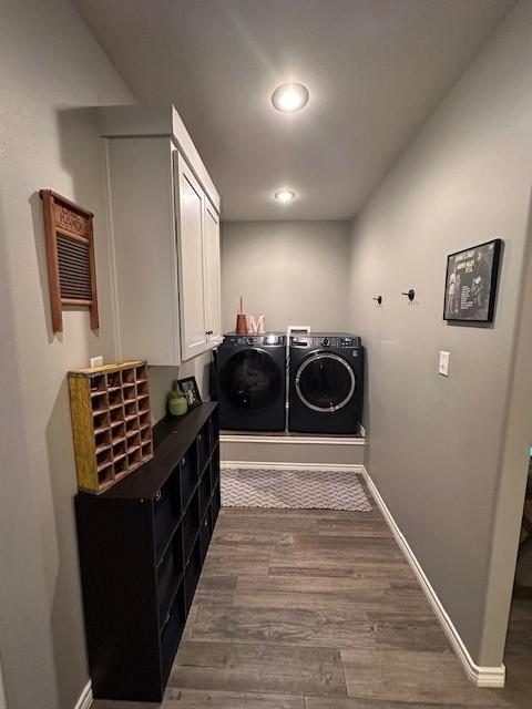 washroom featuring dark wood-type flooring, cabinets, and washer and clothes dryer