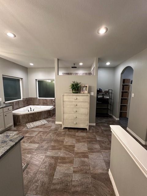 bathroom featuring vanity and a relaxing tiled tub