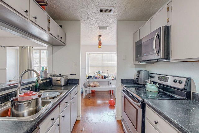 kitchen featuring a textured ceiling, sink, white cabinetry, and stainless steel appliances