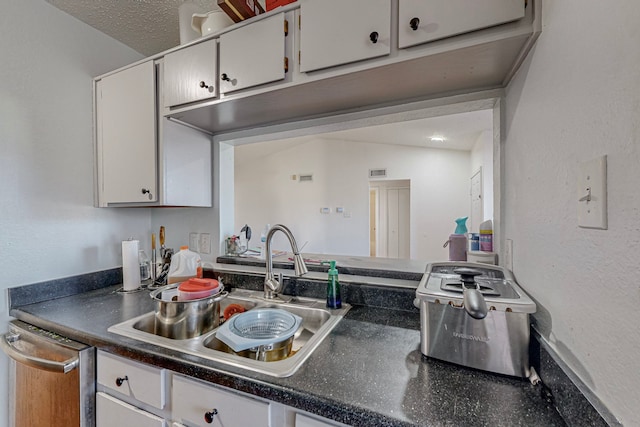 kitchen with white cabinetry, dishwasher, sink, lofted ceiling, and a textured ceiling