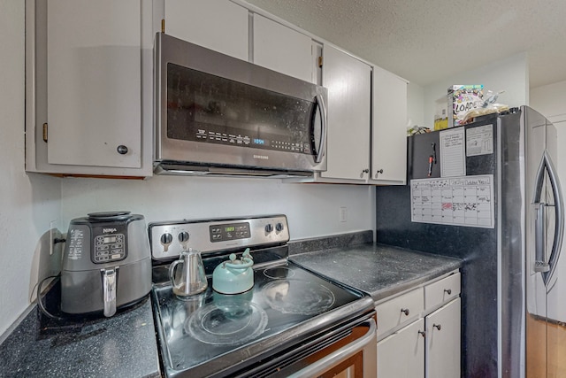 kitchen featuring a textured ceiling, stainless steel appliances, and white cabinetry