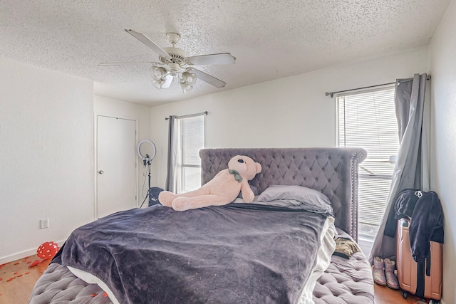 bedroom with ceiling fan, wood-type flooring, and a textured ceiling