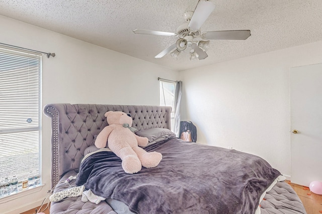 bedroom with ceiling fan, a textured ceiling, and hardwood / wood-style flooring