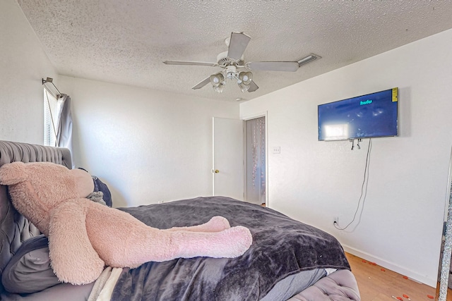 bedroom with hardwood / wood-style floors, a textured ceiling, and ceiling fan