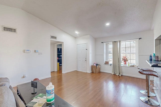 living room with hardwood / wood-style floors, a textured ceiling, and vaulted ceiling