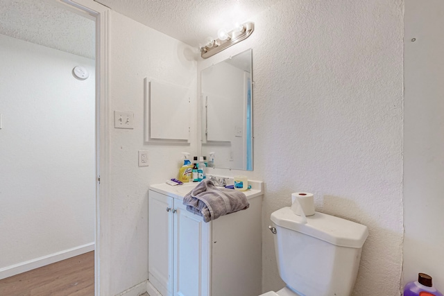 bathroom featuring hardwood / wood-style flooring, vanity, a textured ceiling, and toilet