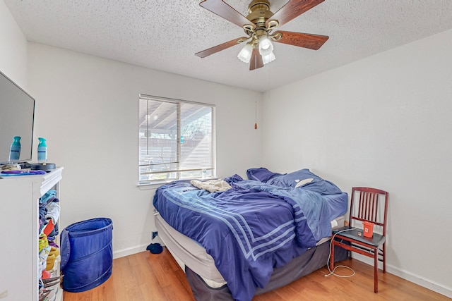 bedroom featuring ceiling fan, hardwood / wood-style floors, and a textured ceiling