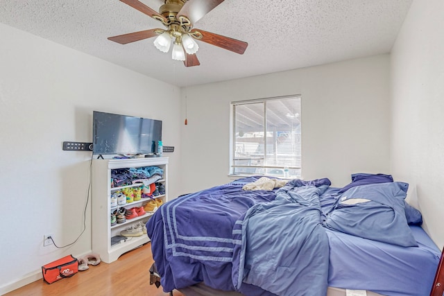 bedroom with hardwood / wood-style floors, ceiling fan, and a textured ceiling