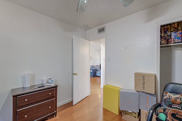 bedroom with ceiling fan, a textured ceiling, and light hardwood / wood-style flooring