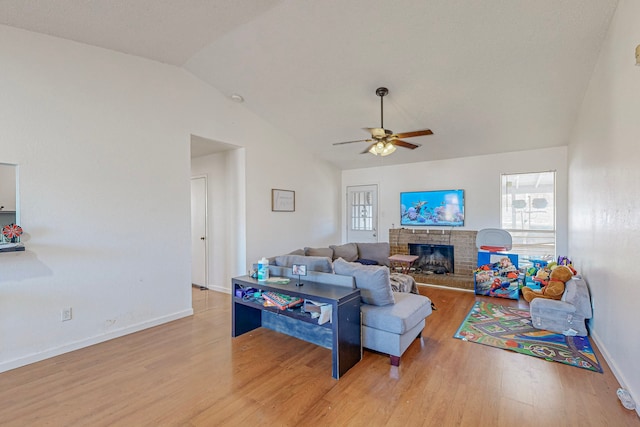 living room with a fireplace, light wood-type flooring, ceiling fan, and lofted ceiling