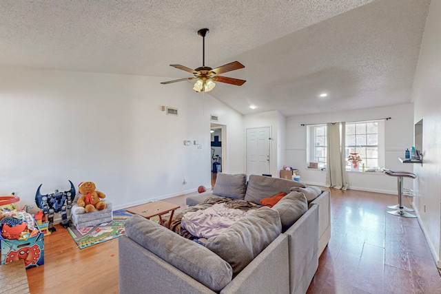 living room with hardwood / wood-style floors, ceiling fan, lofted ceiling, and a textured ceiling