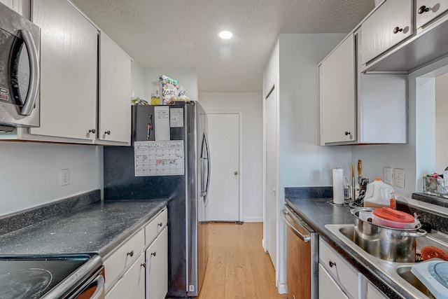 kitchen featuring appliances with stainless steel finishes, a textured ceiling, sink, light hardwood / wood-style flooring, and white cabinets