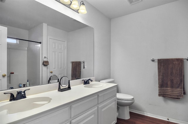 bathroom with a shower, vanity, wood-type flooring, and toilet