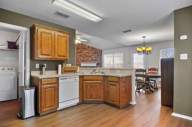 kitchen featuring washer / clothes dryer, sink, dark hardwood / wood-style flooring, white dishwasher, and kitchen peninsula