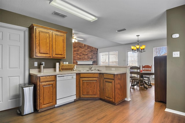 kitchen with kitchen peninsula, ceiling fan with notable chandelier, white dishwasher, sink, and dark hardwood / wood-style floors