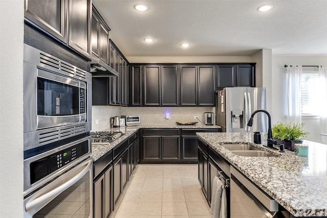 kitchen with sink, light stone countertops, light tile patterned floors, tasteful backsplash, and stainless steel appliances