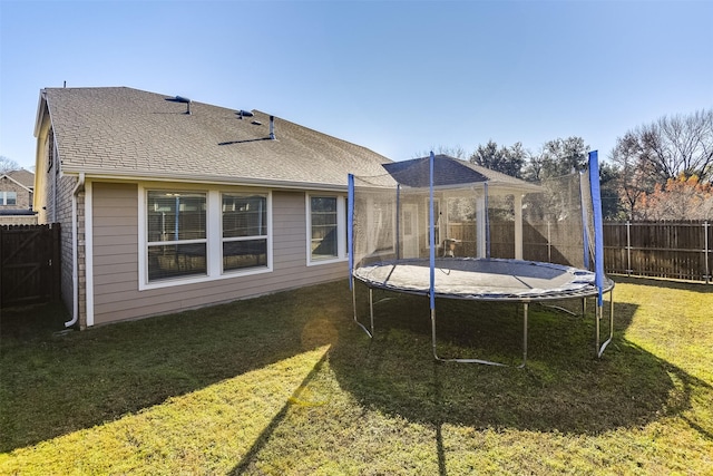 back of house with a trampoline and a yard