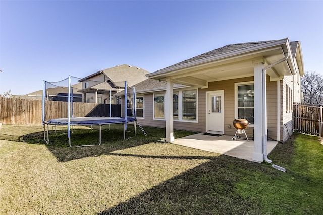 back of property with a yard, a trampoline, and a patio area