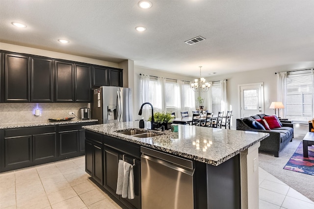 kitchen featuring sink, hanging light fixtures, a notable chandelier, a center island with sink, and appliances with stainless steel finishes