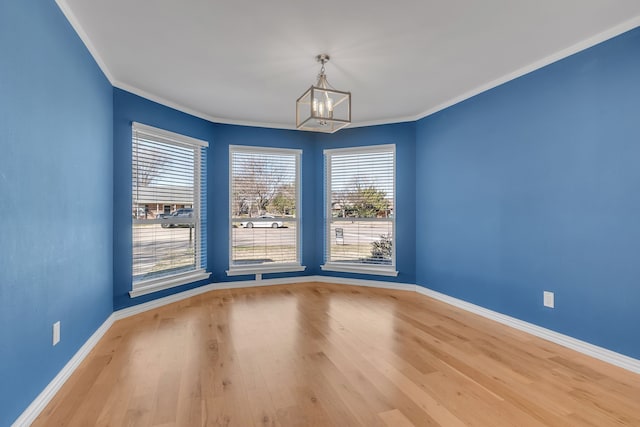 spare room featuring hardwood / wood-style floors, a notable chandelier, and ornamental molding