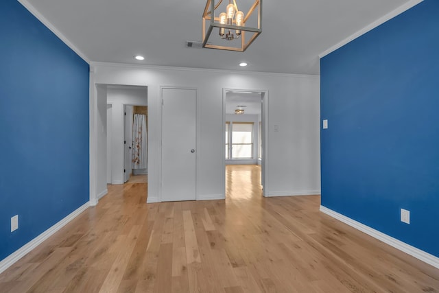 unfurnished room with light hardwood / wood-style floors, ornamental molding, and an inviting chandelier