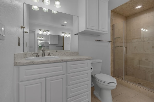 bathroom featuring tile patterned flooring, vanity, toilet, and a shower with door