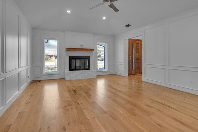 unfurnished living room featuring ceiling fan, light wood-type flooring, and a fireplace