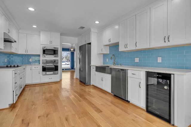 kitchen featuring appliances with stainless steel finishes, light hardwood / wood-style floors, white cabinetry, and wine cooler