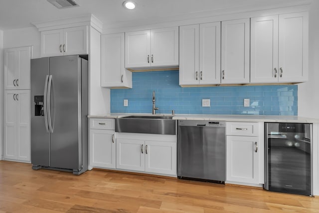 kitchen featuring sink, wine cooler, light hardwood / wood-style floors, white cabinets, and appliances with stainless steel finishes