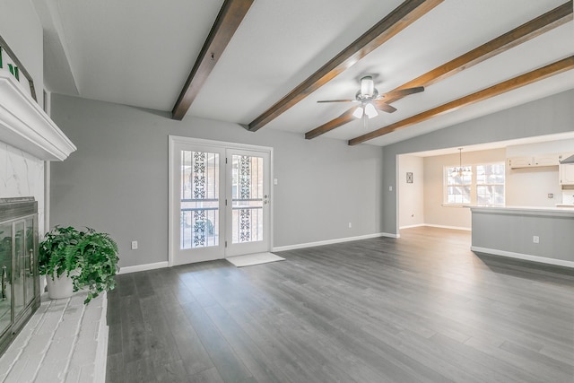 unfurnished living room featuring dark wood-type flooring, ceiling fan with notable chandelier, and vaulted ceiling with beams