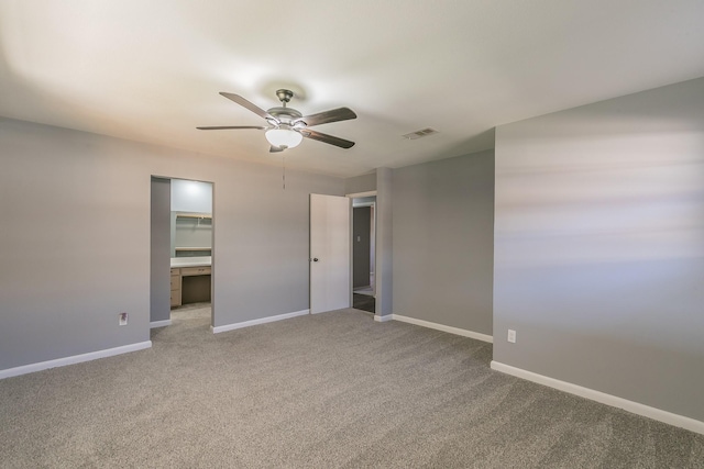 unfurnished bedroom featuring a spacious closet, a closet, ceiling fan, and carpet