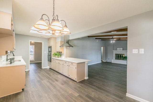 kitchen with pendant lighting, sink, black appliances, beam ceiling, and wall chimney exhaust hood